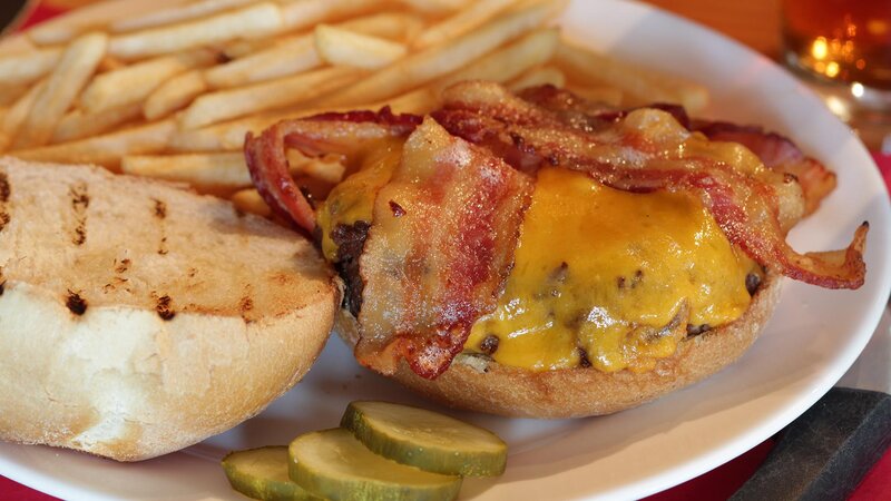 Closeup shot of bacon cheeseburger with side of french fries